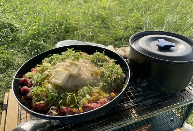 フライパンいっぱいに野菜と食材を炒めている、夏キャンプの調理風景