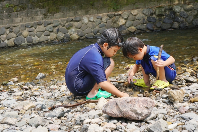 川原でしゃがんで生き物をさがす親子