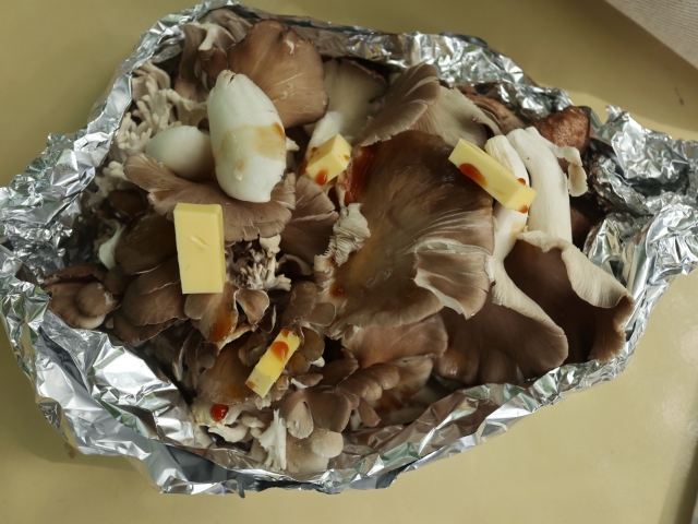 アルミホイルの上に広げたきのことバターのホイル焼き