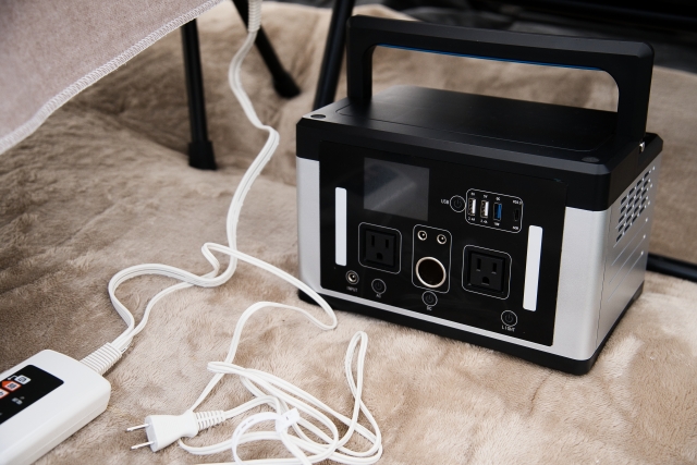 ラグの上のポータブル電源と、つながれた電気毛布のコントローラー
