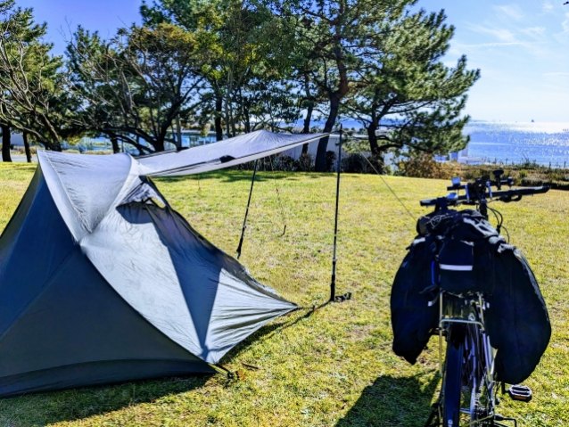 海の見えるキャンプサイトに張ったテントと、パニアバッグを付けた自転車