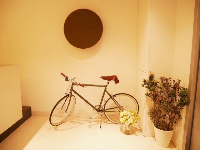 明るい玄関ホールに、スタンドで立てて置いた自転車と観葉植物