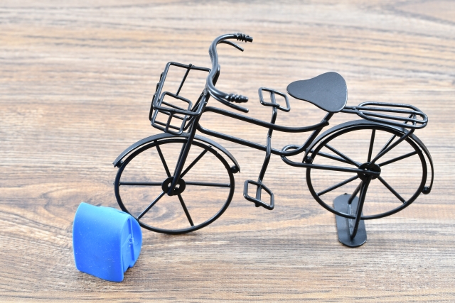 木の床に置いた、かごつき自転車の模型と青いランドセルの模型