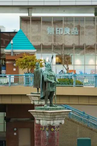 「無印良品」の看板が見える店舗と銅像