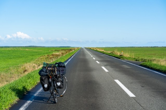 前後にパニアバッグを付けたツーリング自転車と、まっすぐな道